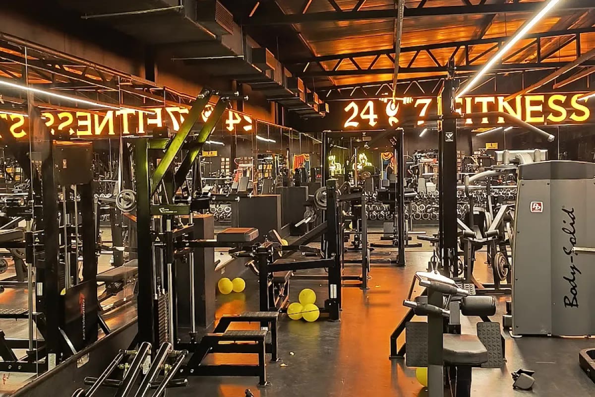 Interior view of 24 7 Fitness Studio with orange lighting, mirrors and strength equipment